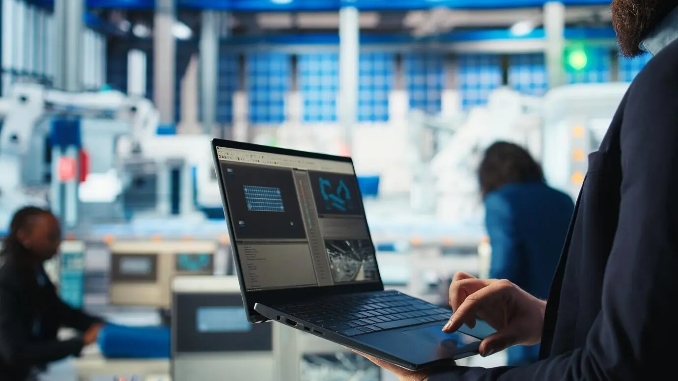 Работник фотовольтаического завода анализирует данные с помощью ноутбука.